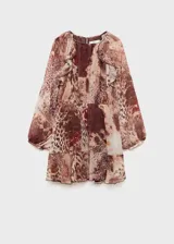 Vestido corto de gasa semitransparente con estampado animal print en tonos marrones. Presenta cuello redondo con detalle fruncido, mangas largas con puños elásticos y volantes decorativos en la parte superior y en el ruedo. Incluye forro interior.