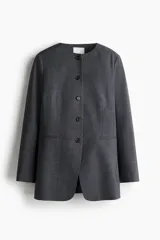 Blazer largo gris con escote redondo, hombreras y cierre frontal de botones. Cuenta con bolsillos delanteros ribeteados, mangas largas y forro interno.
