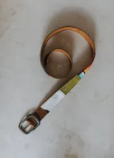 Cinturón de cuero combinado con detalles de aguayo, gamuza verde y pelo blanco, con hebilla metálica rectangular envejecida.