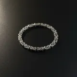 Pulsera de acero inoxidable con diseño de eslabones bizantinos entrelazados, con acabado plateado brillante.