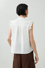 Camisa sin mangas color verde agua con cuello mao, cierre frontal con botones y detalle de puntilla en los hombros.