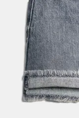 Shorts de jean de algodón, tiro alto, color azul claro desgastado. Presenta cinco bolsillos, cierre frontal con botón metálico y cremallera, y bajo desflecado con vuelta.