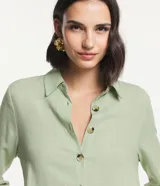 Vestido chemise largo color verde menta, confeccionado en viscolino de marca Marfinno. Presenta cuello solapa, cierre frontal de botones contrastantes, manga larga con trabilla (martingale) y aberturas laterales en el bajo.