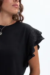 Remera de manga corta color negro, con cuello redondo y detalle de volados en las mangas confeccionados en broderie.