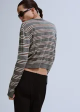 Chaleco de punto sin mangas con cuello redondo y diseño a rayas horizontales en tonos gris y blanco.