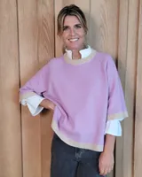 Buzo de lana lambswool en color lila, con cuello redondo, puños y ruedo en tono beige contrastante. Presenta un diseño holgado de manga corta con terminación acanalada.