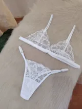 Conjunto de lencería compuesto por un bralette triangular de encaje floral con breteles regulables y una bombacha tipo tanga a juego con detalles de encaje y tiras ajustables.