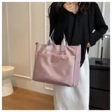 Bolso tipo tote y shopper de color negro, confeccionado en poliéster con amplio espacio interior, doble asa de mano y correa larga ajustable para llevar al hombro o cruzado.
