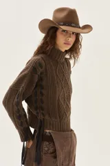 Polera de tejido de punto con diseño de ochos y detalles de tientos en contratono en las mangas. Presenta cuello alto y corte cropped.