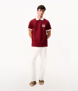 Remera polo azul marino con cuello y puños en contraste de color blanco, manga corta y cierre frontal parcial. Presenta un escudo bordado en el pecho.