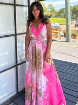 Vestido largo sin mangas con escote en V pronunciado, de corte amplio y fluido, con estampado abstracto en tonos rosados, marrones y blancos, y un cordón trenzado ajustable en la cintura.