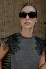 Top gris de cuello redondo y sin mangas, con detalle de flores negras de organza en los hombros.