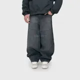 Pantalón de jean estilo ultra baggy, color negro con efecto lavado, de corte muy holgado y tiro medio. Presenta costuras horizontales decorativas en la parte superior y diseño de paneles en las piernas.