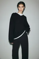 Pantalón ancho de punto color negro, de tiro alto con elástico oculto en la cintura, piernas amplias con pinzas y bolsillos al bies.