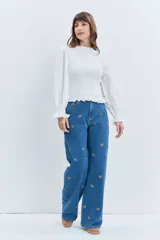 Jean de corte wide leg en color azul medio, con diseño de pequeños bordados dispersos en toda la prenda. Presenta cierre frontal con botón y bolsillos laterales.