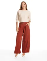 Pantalón de corte palazzo en color terracota, con pierna ancha y caída fluida. Presenta tiro alto con doble abotonadura frontal, pinzas en la cintura y bolsillos laterales funcionales.