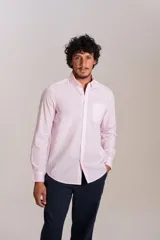 Camisa de manga larga confeccionada en tejido poplin con diseño de rayas verticales finas en color rosado y blanco. Presenta cuello abotonado (button-down), cierre frontal con botones y un bolsillo en el pecho.