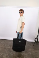 Bolso plateado acolchado con logo ovalado negro y blanco.