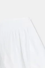 Falda pantalón corta de tiro bajo, color blanco, con forro interior a tono y cierre lateral con cremallera oculta en costura.