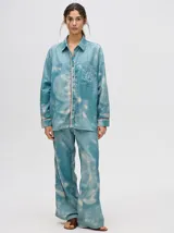 Pantalón de tiro alto con corte recto y holgado, confeccionado en tela liviana con estampado tipo tie-dye en tonos azul y blanco.