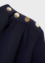 Vestido midi de color azul marino con diseño evasé, cuello barco y manga larga. Presenta cintura fruncida, bajo asimétrico y cierre de cremallera en la parte posterior.