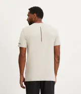 Remera deportiva de hombre con tecnología dry fit, cuello redondo y manga corta. Presenta un diseño liso en color beige con una pequeña etiqueta decorativa en el dobladillo.