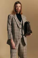 Blazer de corte sastrero con estampado de cuadros en tonos beige, marrones y rojizos. Presenta solapas clásicas, cierre frontal con un botón y bolsillos laterales con solapa.