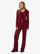 Blusa de manga larga con escote en V, volados frontales y tejido calado semi-transparente, confeccionada en punto liviano de fit ajustado.