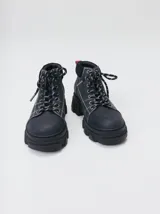Bota acordonada de estilo montañés con suela track de goma robusta. Confeccionada en cuero con detalles de gamuza en la talonera y tirador trasero. Presenta costuras a contratono y cordones bicolores.