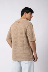 Camisa de punto calado en color beige, de manga corta y corte relajado. Presenta cuello tipo bowling, cierre frontal con botones al tono y una estructura liviana y respirable confeccionada en algodón.