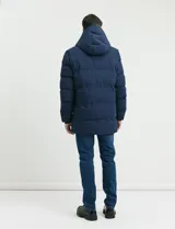 Campera puffer de corte largo, color verde militar, con capucha fija, cierre frontal y puños elásticos internos.