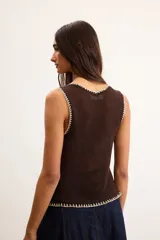 Musculosa de punto color blanco crudo, con escote en V y terminaciones con bordado artesanal amarillo.