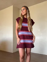 Vestido corto de punto de algodón color bordó, con diseño de rayas horizontales en tonos celestes y rojos, silueta recta y cuello redondo sin mangas.