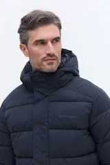 Campera puffer con capucha integrada, cierre frontal cubierto y bolsillos laterales. Confeccionada en nylon, presenta un diseño acolchado y funcional ideal para climas fríos.