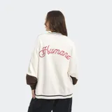 Buzo crewneck de corte boxy y mangas murciélago, con diseño bicolor que combina cuerpo azul y mangas blancas. Presenta detalles de líneas blancas en cuello y ruedo, y letras bordadas en el frente.