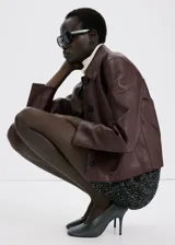 Chaqueta de cuero sintético marrón con cuello camisero, cierre frontal con botones oscuros y bolsillos frontales con solapa.