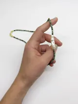 Collar corto de cuentas verdes con una perla de río alargada en el centro.