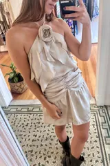 Top color beige claro con escote halter y tres volados. Incluye una rosa de tela removible en el cuello.