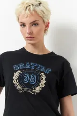 Remera azul marino de algodón con cuello redondo y mangas cortas. Estampa frontal con la palabra "Seattle" en arco, número 38 dentro de un círculo y estrellas.