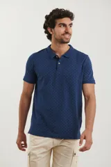 Remera polo de manga corta en color azul oscuro con estampado de pequeños puntos celestes. Presenta cuello clásico, cierre frontal con dos botones y terminaciones acanaladas en las mangas.