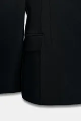 Blazer entallada de Zara Woman Collection, color negro, con escote en pico, manga larga con hombreras y cierre frontal con botones ocultos. Presenta bolsillos con solapa en el delantero y detalle de nervios marcados.