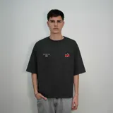 Remera negra de algodón con efecto gastado, corte oversize y estampado en la espalda con una estrella y la palabra "Venefo" en rojo.