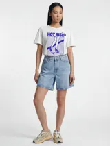 Remera blanca de algodón con efecto lavado y terminación gastada en el cuello, las mangas y el ruedo. Presenta estampa frontal con la leyenda "Hot Risk" y una ilustración en tonos azules de unas piernas sobre un skate.