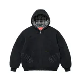 Campera con capucha Supreme de lona color negro, con cierre frontal y bolsillos tipo canguro. Presenta apliques de cuero con tipografía gótica en la parte inferior y forro interior de tela a cuadros.