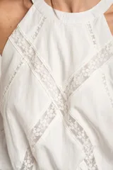 Top de viscosa y poliamida color blanco, con cuello halter y detalles de inserciones de encaje transparente formando una equis en el frente.