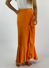 Pollera larga color naranja, de corte recto y con volados en diagonal en el frente.