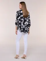Blusa de gasa de calce suelto y caída ligera, color azul con estampado floral blanco. Presenta escote en V con cuello mao, tabla central, mangas largas regulables con presilla y botón, ruedo redondeado de estilo mullet y espalda con canesú y pliegue central.