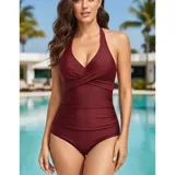 Malla entera de color verde oscuro, combinada con un diseño floreado en la parte inferior. Presenta escote halter cruzado y fruncidos en la zona del abdomen.