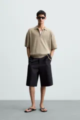 Polo de punto color verde oliva, de manga corta y corte relajado. Presenta cuello solapa con cierre frontal de cremallera.