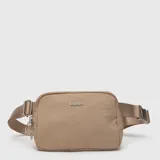 Riñonera Bubba color beige, con diseño minimalista, compartimento principal con cierre y correa ajustable con hebilla metálica.